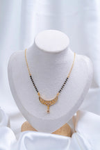 Traditional Filigree Crescent Mangalsutra flat lay on peach background - Nyara